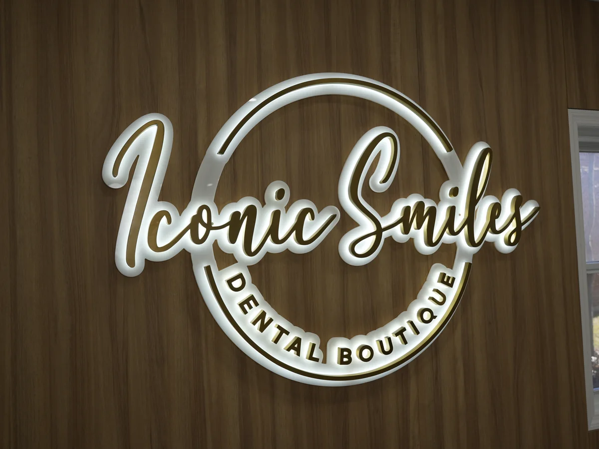 Illuminated Iconic Smiles Dental Boutique sign on the wood-paneled wall of the Freeport office