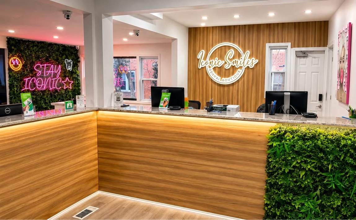 Reception desk at the Bellerose office, with the Iconic Smiles sign on a wood wall and a Stay Iconic neon on a green feature wall