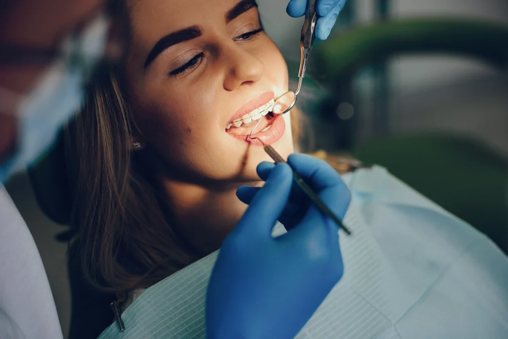 A Bellerose dentist using a dental mirror and probe to examine a patient's smile, discussing secure tooth replacement options for missing back teeth.
